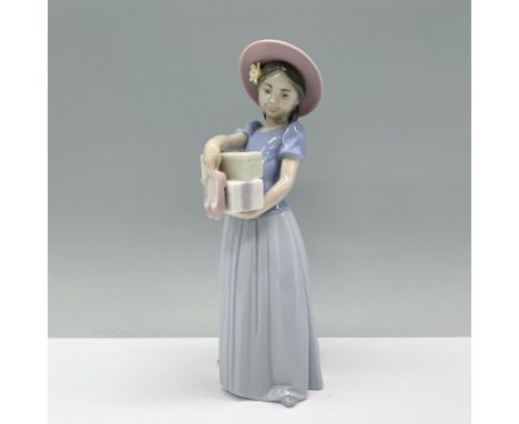 A young girl in her Sunday best holds a pair of new shoes with excitement. Lladro backstamp. This item has its original box w