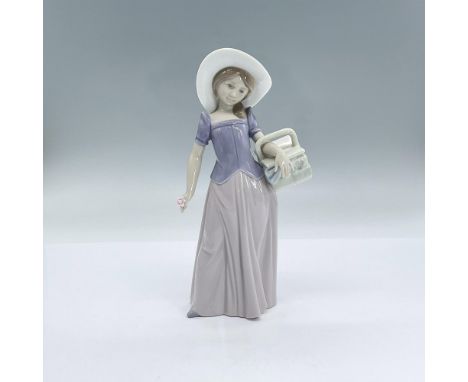 A glossy figure of a woman adorned with a white hat, holding a basket and holding a pink flower. November 15 1997 Event Figur