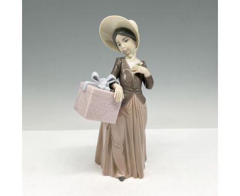 Glossy figure dressed in brown with cream colored bonnet holding large, gift-wrapped box. Lladro backstamp. This item has its