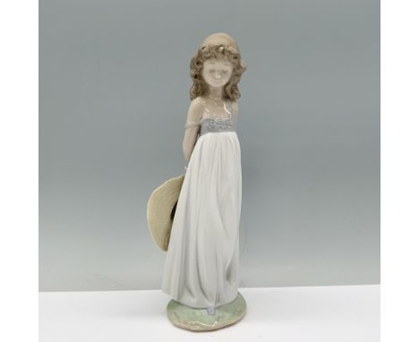 Clad in a white sundress, the girl shyly holds her sunhat behind her back. Lladro backstamp. This item has its original box w