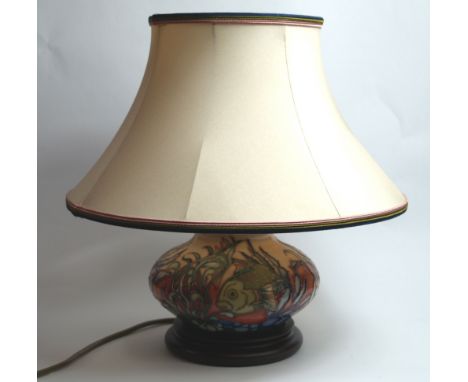 Moorcroft, a relief tube-line decorated electric table lamp with shade, raised on a mahogany plinth. Height (including shade)