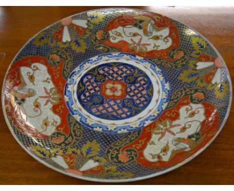 An early 19th Century Japanese ceramic charger, colours from the Imari pallette, with gilt highlights and painted four charac