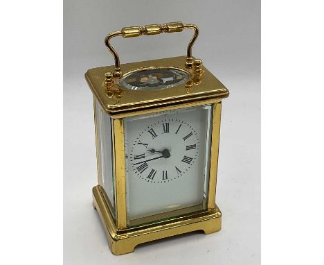 An early 20th century French brass cased carriage clock, with Roman numerals to the white enamelled dial, contained within th