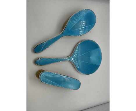 A silver dressing table set with blue enamel back plates comprising brushes and hand mirror