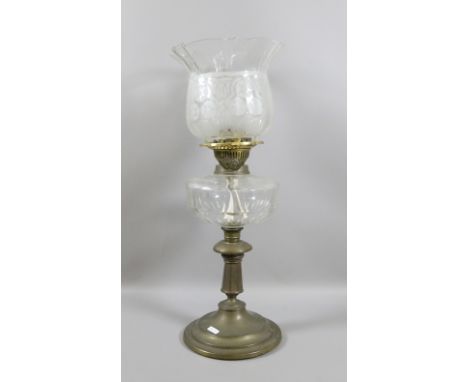 A brass based oil lamp with cut glass font and etched shade.