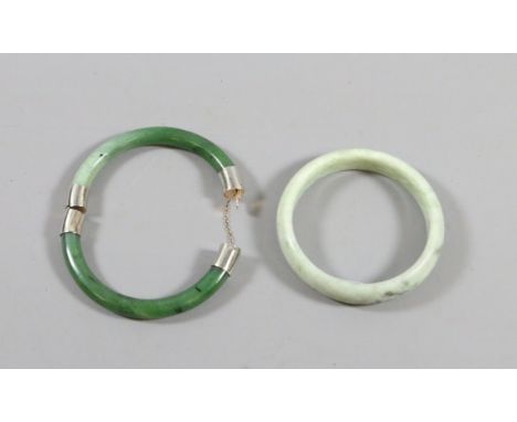 A Chinese spinach jade bangle with white metal hinge and clasp along with a similar pale jade coloured bangle.