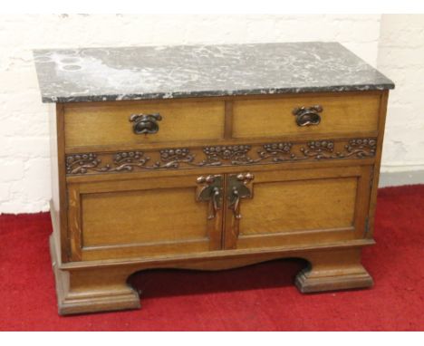 An Art Nouveau light oak marble top washstand by T B & W Cockayne Sheffield with stylized handles, carved frieze and raised o