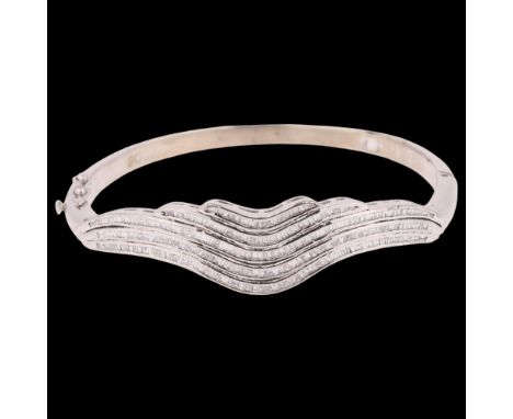 A 9ct white gold diamond hinged bangle, channel set with baguette-cut diamonds, total diamond content approx 3ct, setting hei