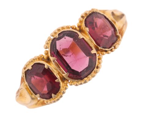 An Antique Georgian three-stone garnet ring, collet set with octagonal step-cut garnets, within beaded edge and chased scroll