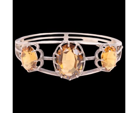 A silver citrine hinged bangle, unmarked, setting height 21.4mm, internal circumference 16cm, 30g . Condition Report: Citrine
