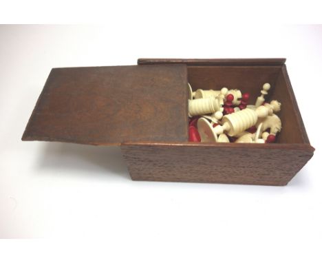 A stained ivory chess set, 19th century, of turned form, the King 8cm high, in a mahogany box with sliding cover.