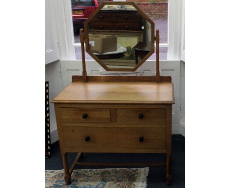 A light oak Arts & Crafts dressing table, with octagonal mirror, two short and one long drawer on turned legs, 92cm wide.