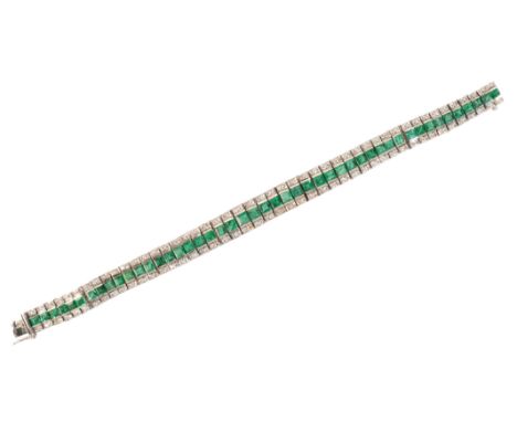 AN EMERALD AND DIAMOND BRACELETin 18ct white gold, set with a row of calibré cut emeralds, totalling c.9.40 carats, flanked b