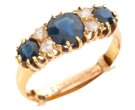 AN ANTIQUE SAPPHIRE AND DIAMOND RINGin 18ct gold, set with three graduated cushion cut sapphires, alternating with pairs of r