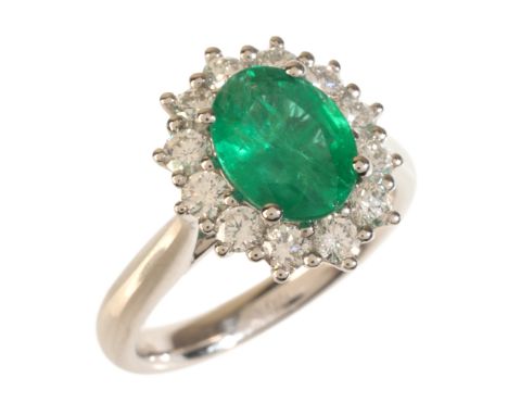 AN EMERALD AND DIAMOND CLUSTER RINGin platinum, set with an oval cut emerald of c.1.44 carats, surrounded by a cluster of rou