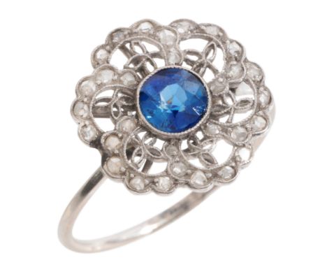 A SAPPHIRE AND DIAMOND CLUSTER RINGin platinum, set with a round cut sapphire of c.0.60, to an open-work cluster set througho