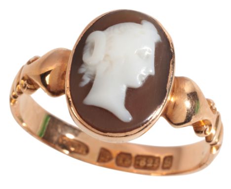 AN ANTIQUE CAMEO RINGin 15ct gold, set with a helmet shell cameo carved to depict the profile of a woman, held in a bezel set