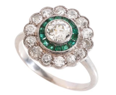 A DIAMOND AND EMERALD CLUSTER RINGin platinum, set with an old cut diamond of c.0.62 carats, held in a bezel setting, surroun