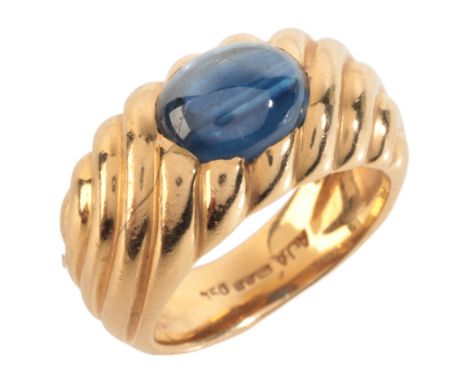 A SAPPHIRE DRESS RINGin 18ct gold, set with a sapphire cabochon of c.3.17 carats, over a stylised design, British import mark