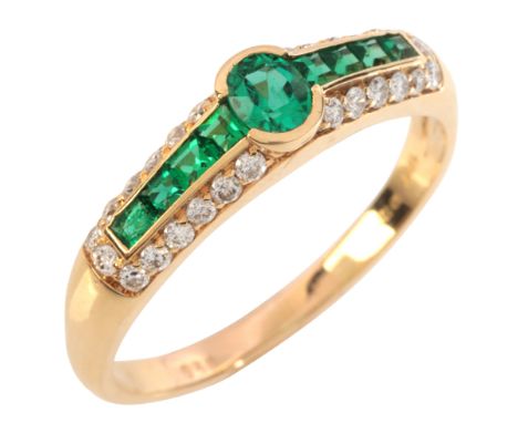 AN EMERALD AND DIAMOND RINGin 18ct gold, set with an oval cut emerald, to shoulders set with calibré cut emeralds, surrounded