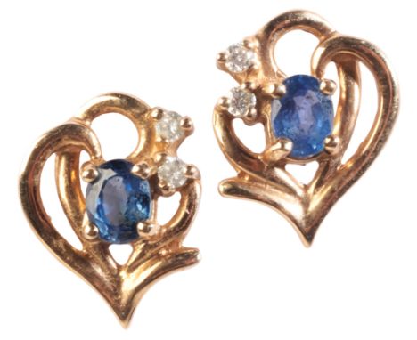 A PAIR OF SAPPHIRE AND DIAMOND STUD EARRINGSin 9ct gold, each set with an oval-cut sapphire over a stylised design, accented 