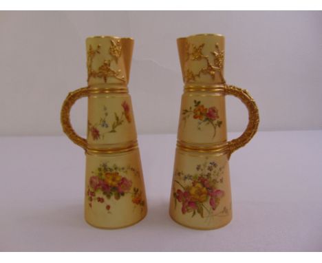 A pair of Royal Worcester blush ivory jugs painted with flowers and gilded decorations