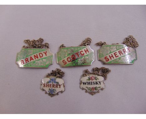 A pair of silver and enamel wine labels and three silver plated and enamel wine labels all with suspensory chains