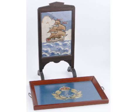A tea tray with cross-stitch wool Royal Navy Crest,
length 23.5" and an oak framed firescreen with woolwork sailing ship, (2)