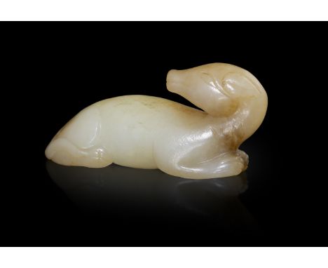 A CELADON RUSSET JADE DOGChina, Ming dynasty.Carved in recumbent position with head turned sharply back, the front paws held 