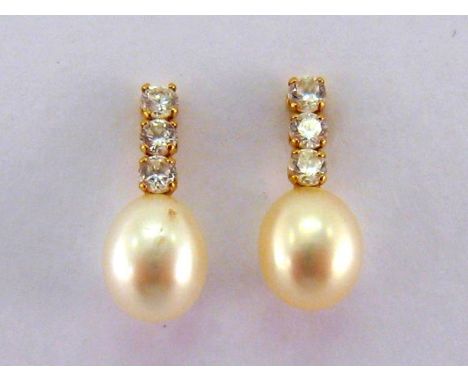 A pair of fresh water cultured pearl and cubic zirconia ear studs, the off round pearls 6.8mm long, mounted in 18 carat yello