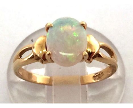 An opal ring, the oval precious opal cabochon 8.9 x 6.9mm, the shank stamped '18k', closed back setting, finger size M/N, 2.7