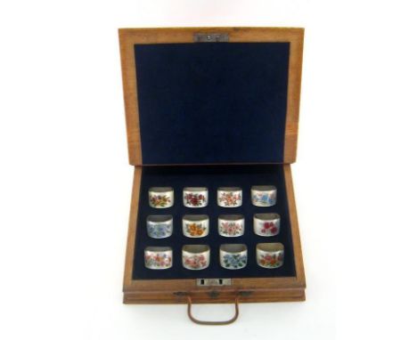 A set of 12 silver and enamel napkin rings, mark of RL, Birmingham, 1975, with curved fronts, each enamelled with different t