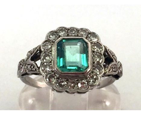 An Art Deco emerald and diamond cluster ring, the central emerald cut approx. 1.14 carats, in a surround of eight cuts, to ro