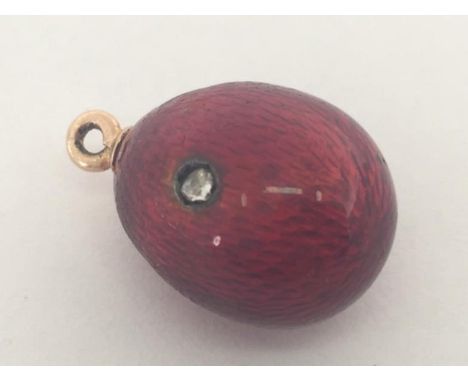 A gold, diamond and enamel egg pendant, circa 1910, the ovoid body of red guilloche enamel and set with a single rose cut, 18