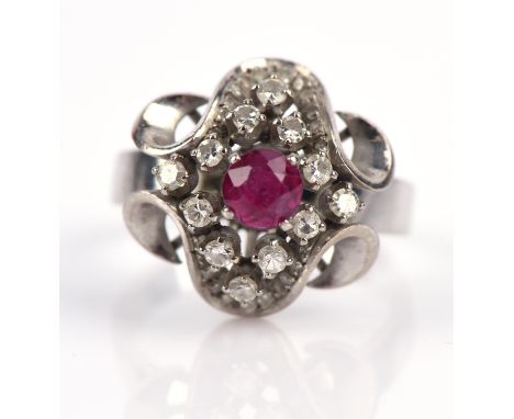 Ruby and diamond modernist ring, set with a central round cut ruby, surrounded by single cut diamonds with a ribbon surround 