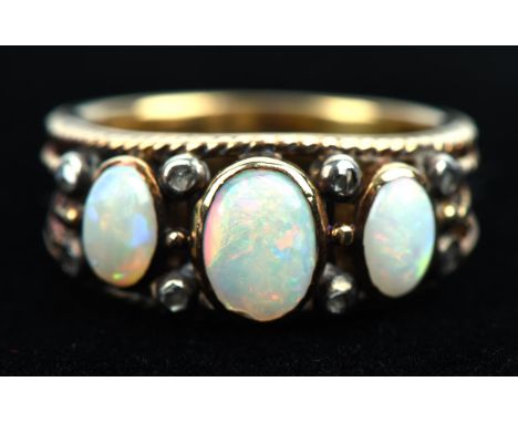 Opal and diamond ring, set with three oval cabochon cut opals, separated by rose cut diamonds, with rope detail edges and sho