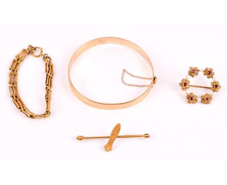 A collection of 9 ct gold items including a hinged bangle, a child's gate bracelet, a clove bar brooch, and a circular ruby a