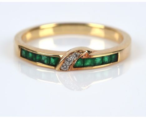 Emerald and diamond dress ring, with a row of channel set square step cut emeralds, with three round brilliant diamonds set t