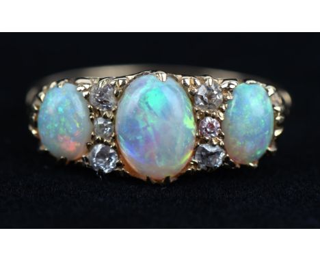 Opal and diamond ring, with three oval cabochon opals, and old cut diamonds, with carved sides, in stamped 18 ct with makers 