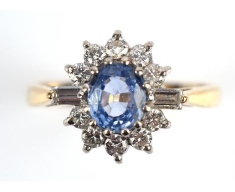 A sapphire and diamond cluster ring, central oval cut sapphire weighing an estimated 0.70 carats, surrounded by round brillia