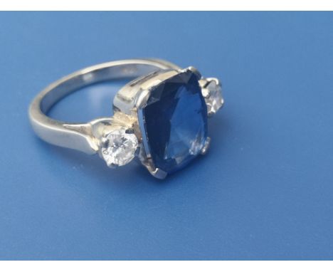 A sapphire &amp; diamond three stone  ring, the rectangular four-claw set sapphire weighing approximately 5 carats, flanked b