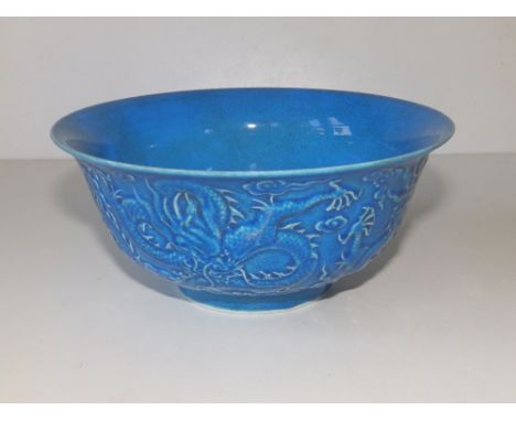 A Chinese blue glazed bowl decorated in relief with a dragon, seal mark to underside, 6.3" diameter - small rim chip.