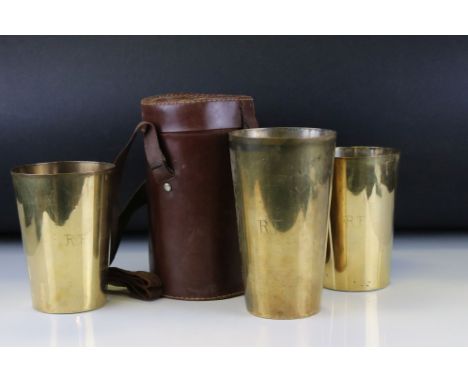 A vintage leather cased set of three brass beakers / cups 