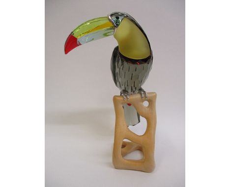A Swarovski coloured glass model toucan with cast metal feet perched on a carved wood base, 7 6/8 h
