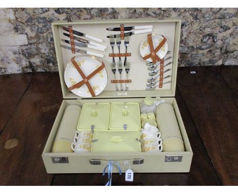 A mid 20th century Coracle picnic hamper with a cream and brown vinyl clad case enclosing chrome cutlery, china cups and plat