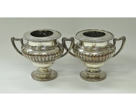 A pair of large 19th Century Sheffield plate wine coolers of urn form with twin handles, part reeded bodies, raised on steppe