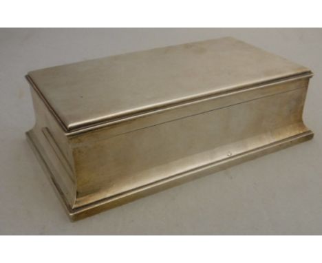 A George V silver table mounted cigarette box of rectangular form on flared stepped base (by Sebastian Henry for R &amp; S Ga