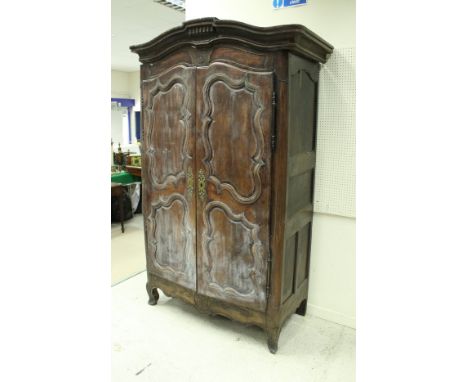 A 19th Century French walnut armoire, the shaped upper frieze with floral medallion decoration over two cupboard doors and si