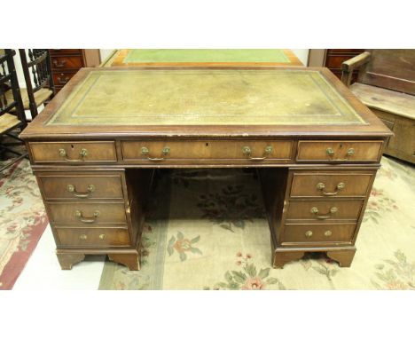 A modern mahogany kneehole desk, the tooled and gilded leather insert top over three frieze drawers on two banks of three dra