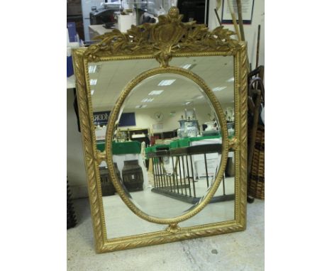 A carved giltwood and gesso framed wall mirror in the George III taste the foliate and dragon scale carved surmount over a ce